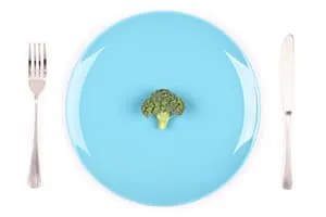 brocoli seul dans une assiette bleu entouré de couverts