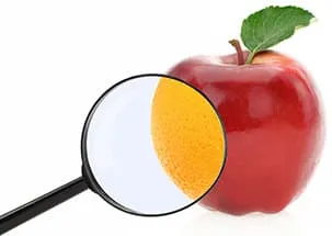 pomme rouge avec une loupe montrant une orange sur un fond blanc