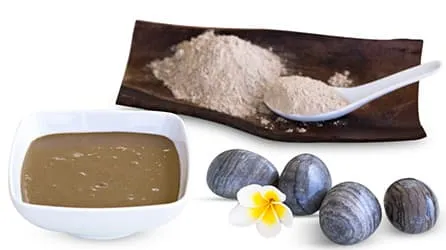 poudre marron et bol blanc avec des cailloux noir sur un fond blanc poudre marron et bol blanc avec des cailloux noir sur un fond blanc