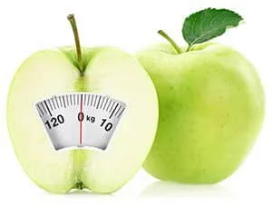 deux pommes vertes avec une balance sur un fond blanc