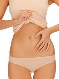 femme svelte en petite tenue touchant son ventre sur un fond blanc