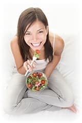 femme blanche souriante mangeant des fraises sur son canapé