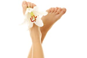 paire de pieds de femme en l'air avec une fleur blanche posée dessus
