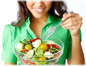 femme avec un chemiser vert mangeant une salade composée