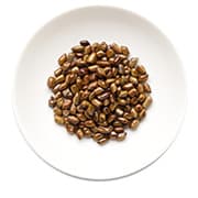 un tas de grains de café marron dans une assiete blanche