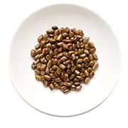 un tas de grains de café marron dans une assiete blanche