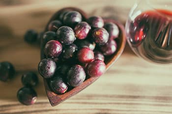 raisins rouges dans un recipient en bois sur une table en bois raisins rouges dans un recipient en bois sur une table en bois