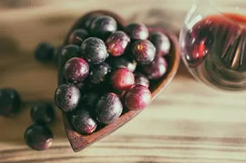 raisins rouges dans un recipient en bois sur une table en bois
