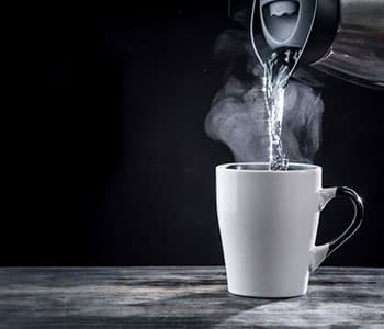 eau chaude versée d'une bouilloire dans une tasse à thé eau chaude versée d'une bouilloire dans une tasse à thé