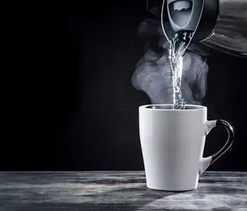 eau chaude versée d'une bouilloire dans une tasse à thé