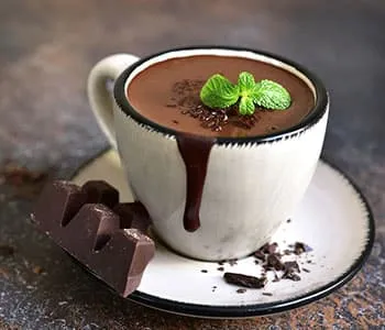 tasse de chocolat chaud sur une assiette avec un carré de chocolat