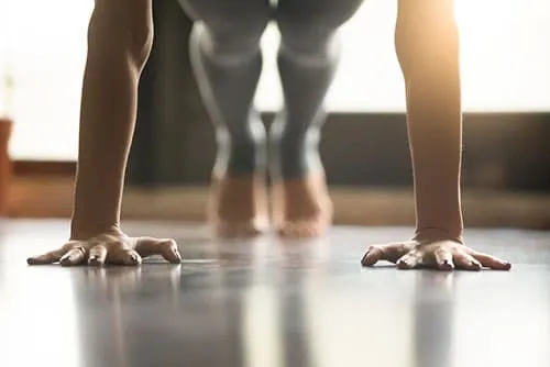 femme en leggin en train de faire des répulsions au sol