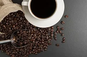 Tasse de café avec grains de café éparpillés autour