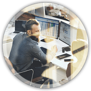 man sitting at a desk working on a computer with multiple screens