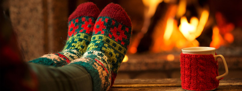 femme avec des chaussettes de Noël à côté du feu avec une tasse de thé femme avec des chaussettes de Noël à côté du feu avec une tasse de thé