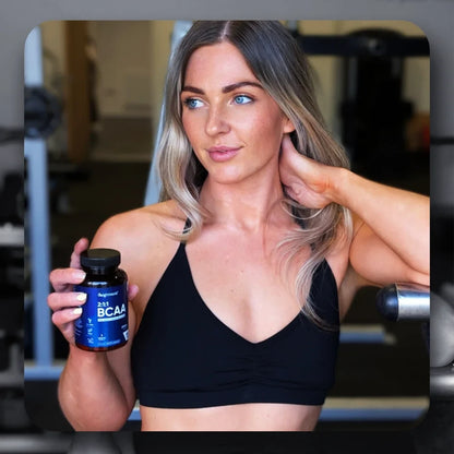 Femme tenant un flacon BCAA 2:1:1 WeightWorld à côté d’un shaker