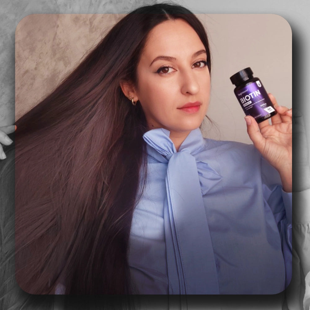 Flacon de biotine tenu par une femme, coiffure sombre, tenue bleue