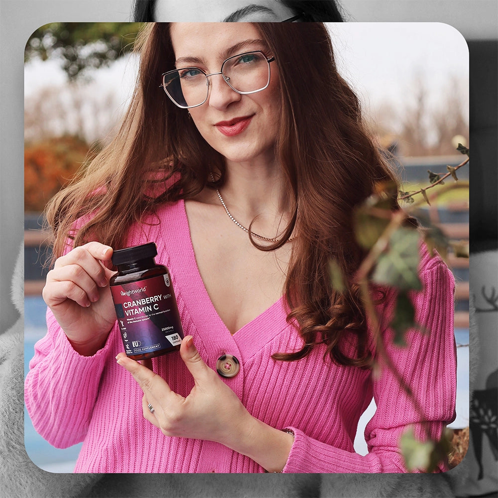 Flacon de compléments Cranberry et vitamine C tenu par une femme, 180 gélules